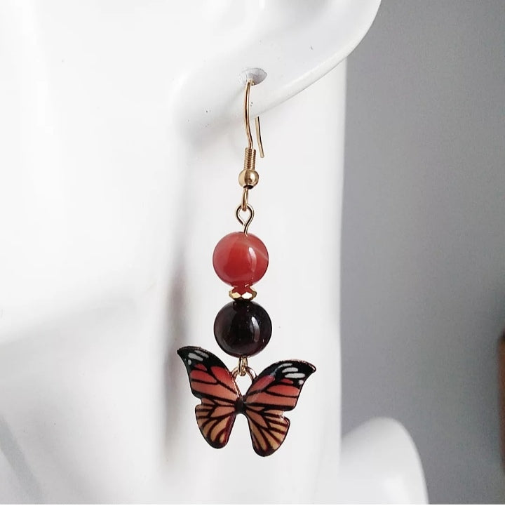 Boucles d'oreilles en pierres naturelles Cornaline & Œil de Taureau avec pendentif papillon – énergie, protection et ancrage. Un bijou spirituel pour vitalité, confiance et équilibre.
