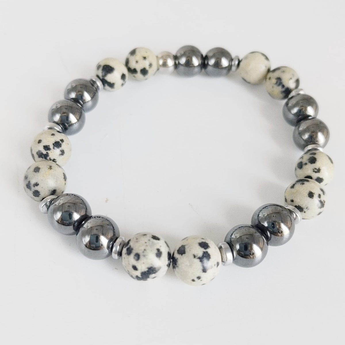 Parure Hématite & Jaspe Dalmatien en pierres naturelles : collier, bracelet ou boucles d’oreilles. Une association symbolique entre ancrage, équilibre et protection.