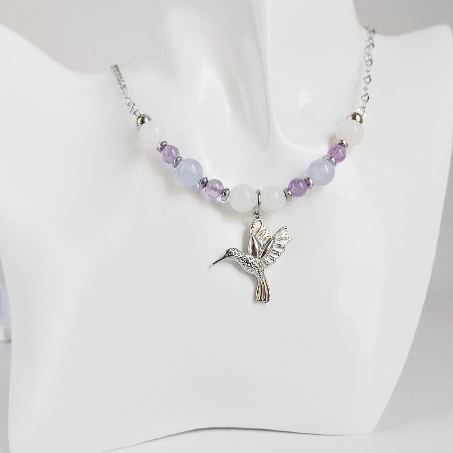 Découvrez notre collier Colibri en Jade blanc, Calcédoine et Améthyste. Un bijou artisanal en pierres naturelles synonyme de sérénité, clarté et douceur.