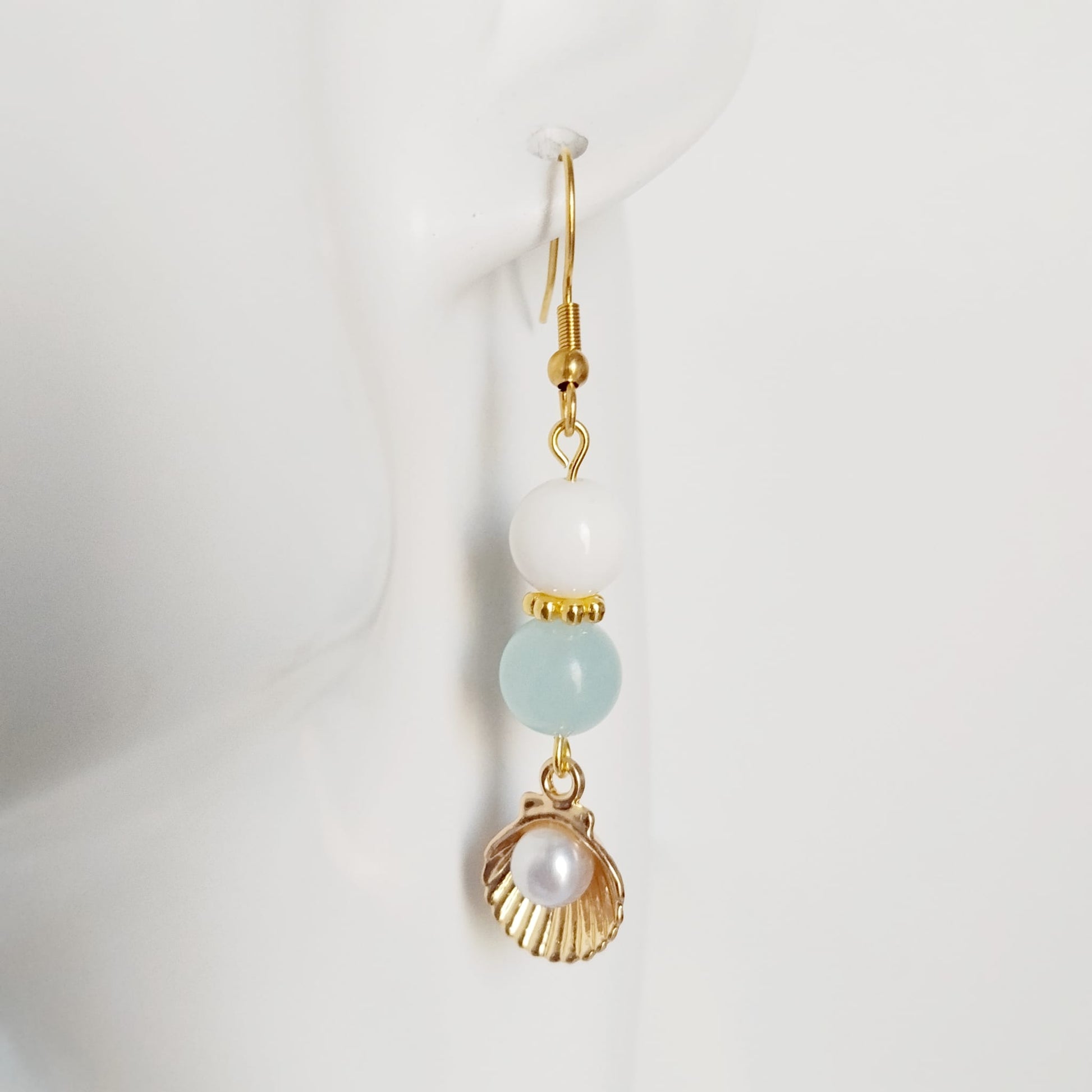 Découvrez les boucles d'oreilles en Aigue-Marine, Nacre et Saint-Jacques. Des bijoux sacrés en acier inoxydable pour illuminer le visage et apaiser l'esprit.