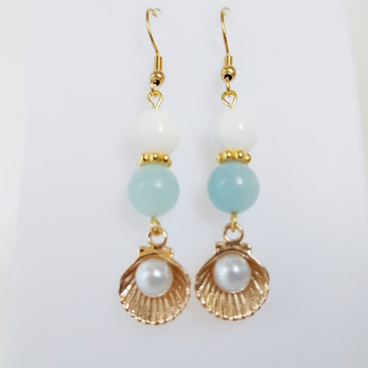 Découvrez les boucles d'oreilles en Aigue-Marine, Nacre et Saint-Jacques. Des bijoux sacrés en acier inoxydable pour illuminer le visage et apaiser l'esprit.