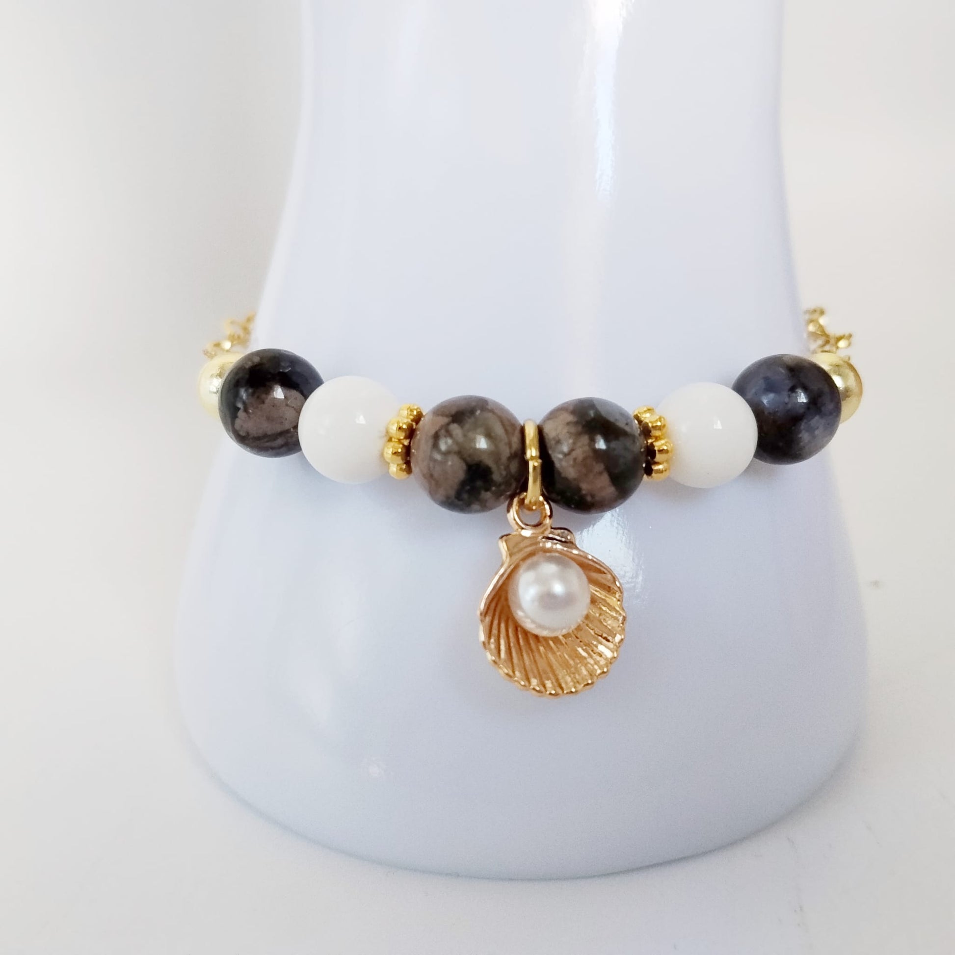 Équilibrez vos énergies au quotidien avec notre bracelet ajustable en Agate Turitelle, Nacre et son pendentif Saint-Jacques protecteur. Conçu en acier inoxydable.