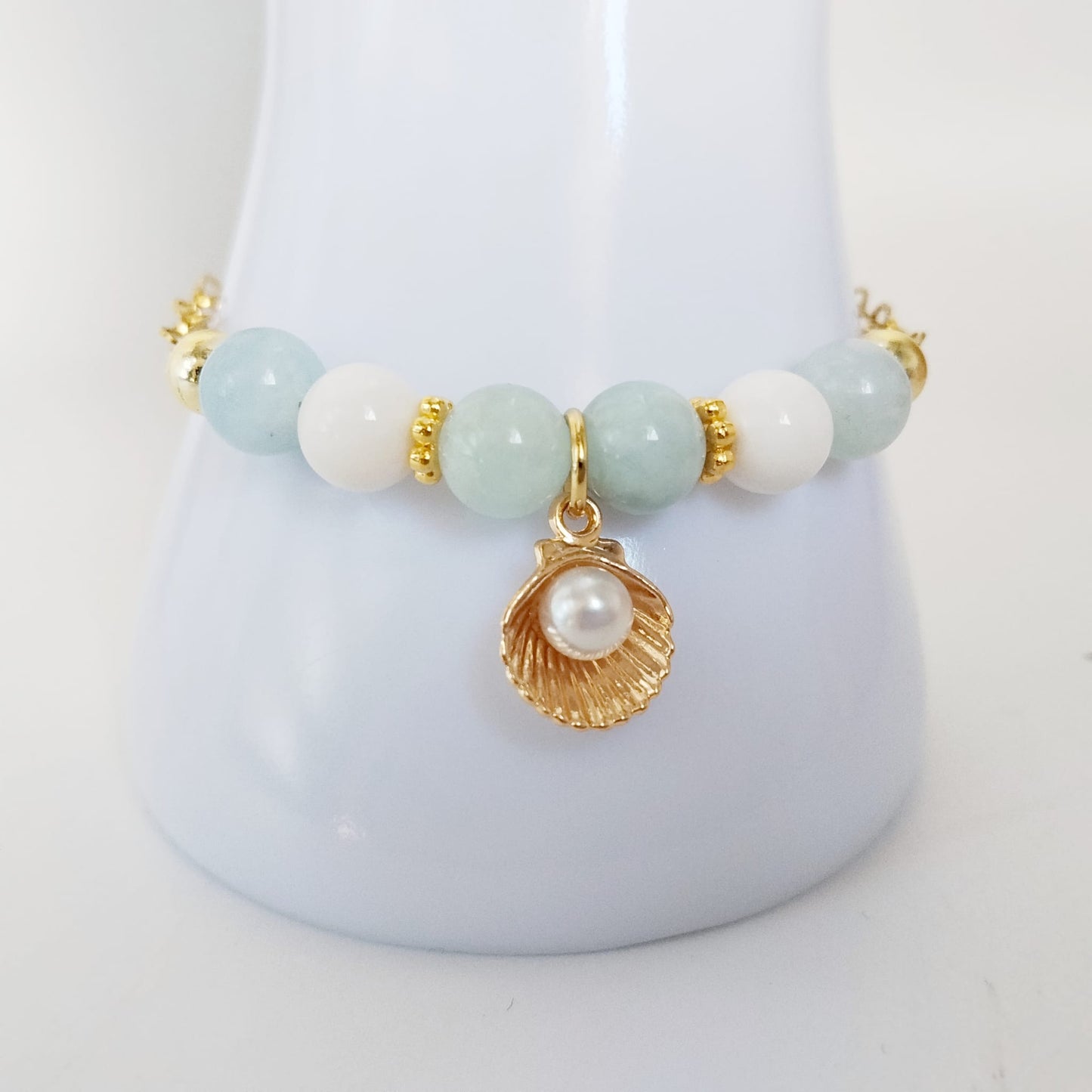 Découvrez notre bracelet ajustable en Aigue-Marine, Nacre et pendentif Saint-Jacques. Un bijou de lithothérapie en acier inoxydable, doux et protecteur au quotidien.