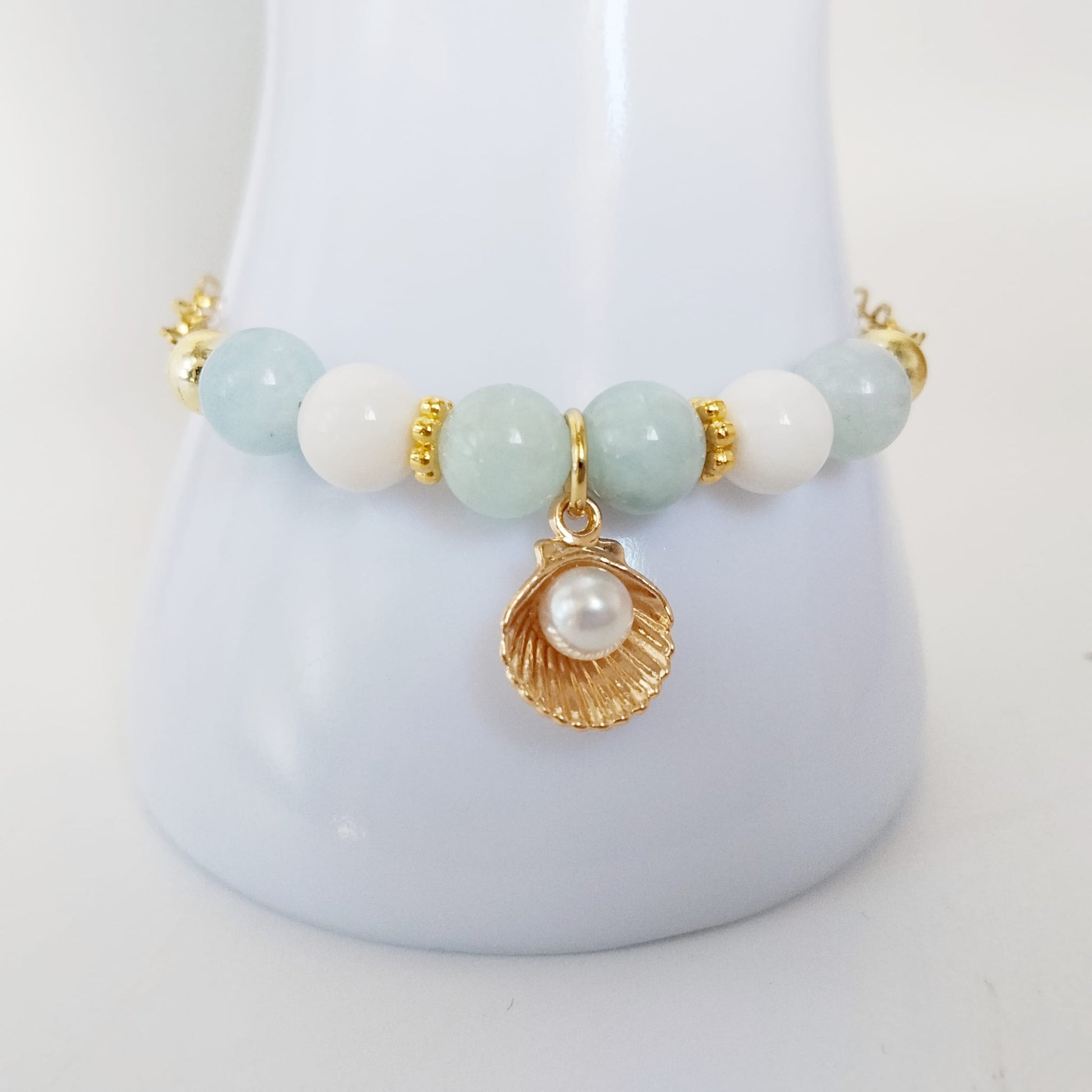 Découvrez notre bracelet ajustable en Aigue-Marine, Nacre et pendentif Saint-Jacques. Un bijou de lithothérapie en acier inoxydable, doux et protecteur au quotidien.