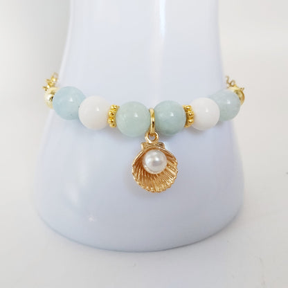 Découvrez notre bracelet ajustable en Aigue-Marine, Nacre et pendentif Saint-Jacques. Un bijou de lithothérapie en acier inoxydable, doux et protecteur au quotidien.