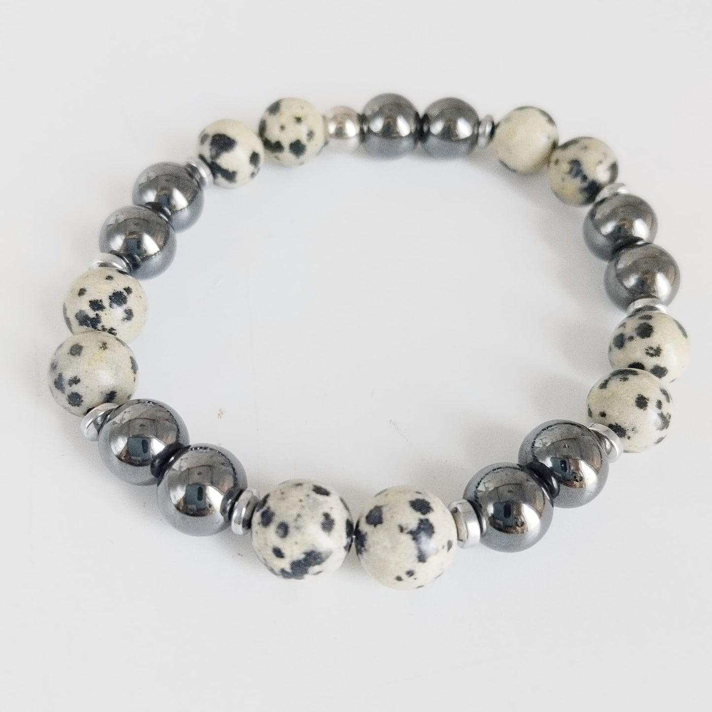 Parure Hématite & Jaspe Dalmatien en pierres naturelles : collier, bracelet ou boucles d’oreilles. Une association symbolique entre ancrage, équilibre et protection.