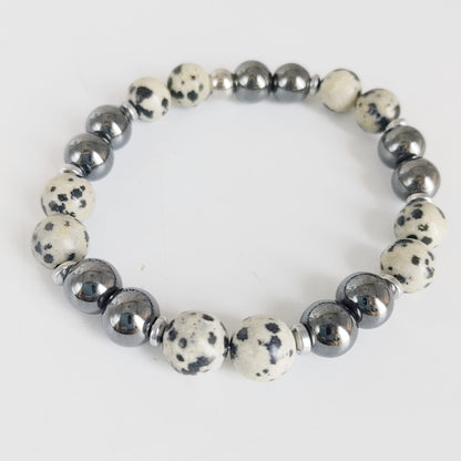 Parure Hématite & Jaspe Dalmatien en pierres naturelles : collier, bracelet ou boucles d’oreilles. Une association symbolique entre ancrage, équilibre et protection.