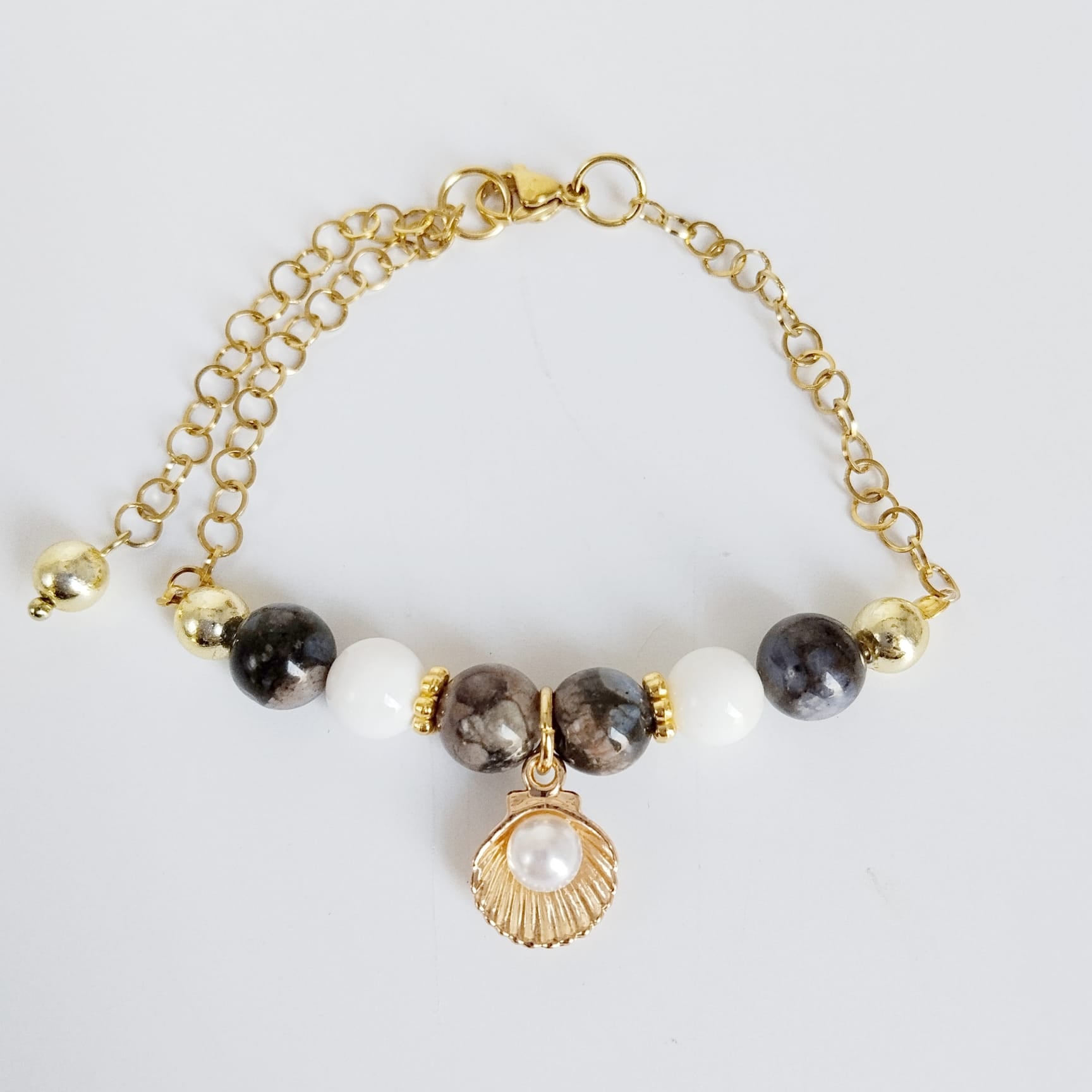 Équilibrez vos énergies au quotidien avec notre bracelet ajustable en Agate Turitelle, Nacre et son pendentif Saint-Jacques protecteur. Conçu en acier inoxydable.