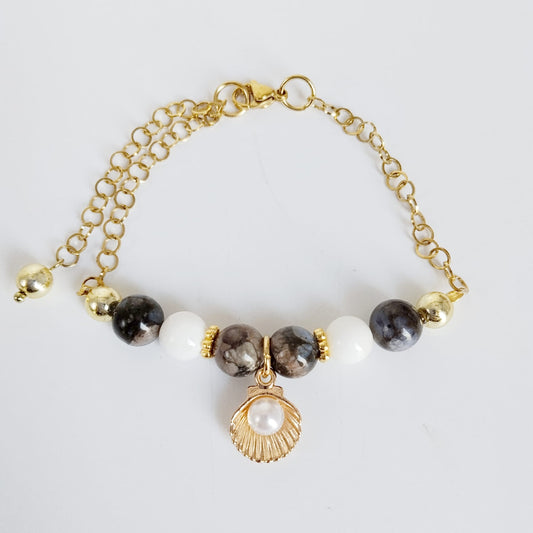 Équilibrez vos énergies au quotidien avec notre bracelet ajustable en Agate Turitelle, Nacre et son pendentif Saint-Jacques protecteur. Conçu en acier inoxydable.