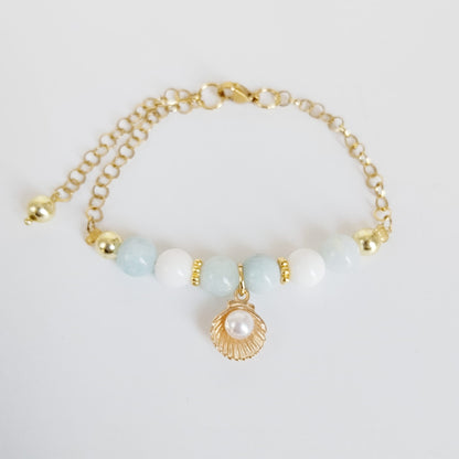 Découvrez notre bracelet ajustable en Aigue-Marine, Nacre et pendentif Saint-Jacques. Un bijou de lithothérapie en acier inoxydable, doux et protecteur au quotidien.