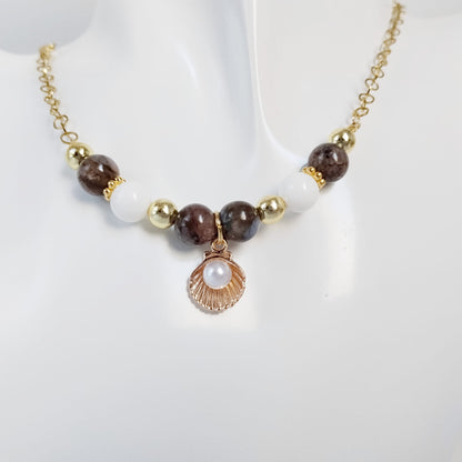 Découvrez le collier en Agate Turitelle, Nacre et pendentif Saint-Jacques. Un bijou artisanal unique alliant ancrage, douceur océanique et élégance en acier inoxydable.