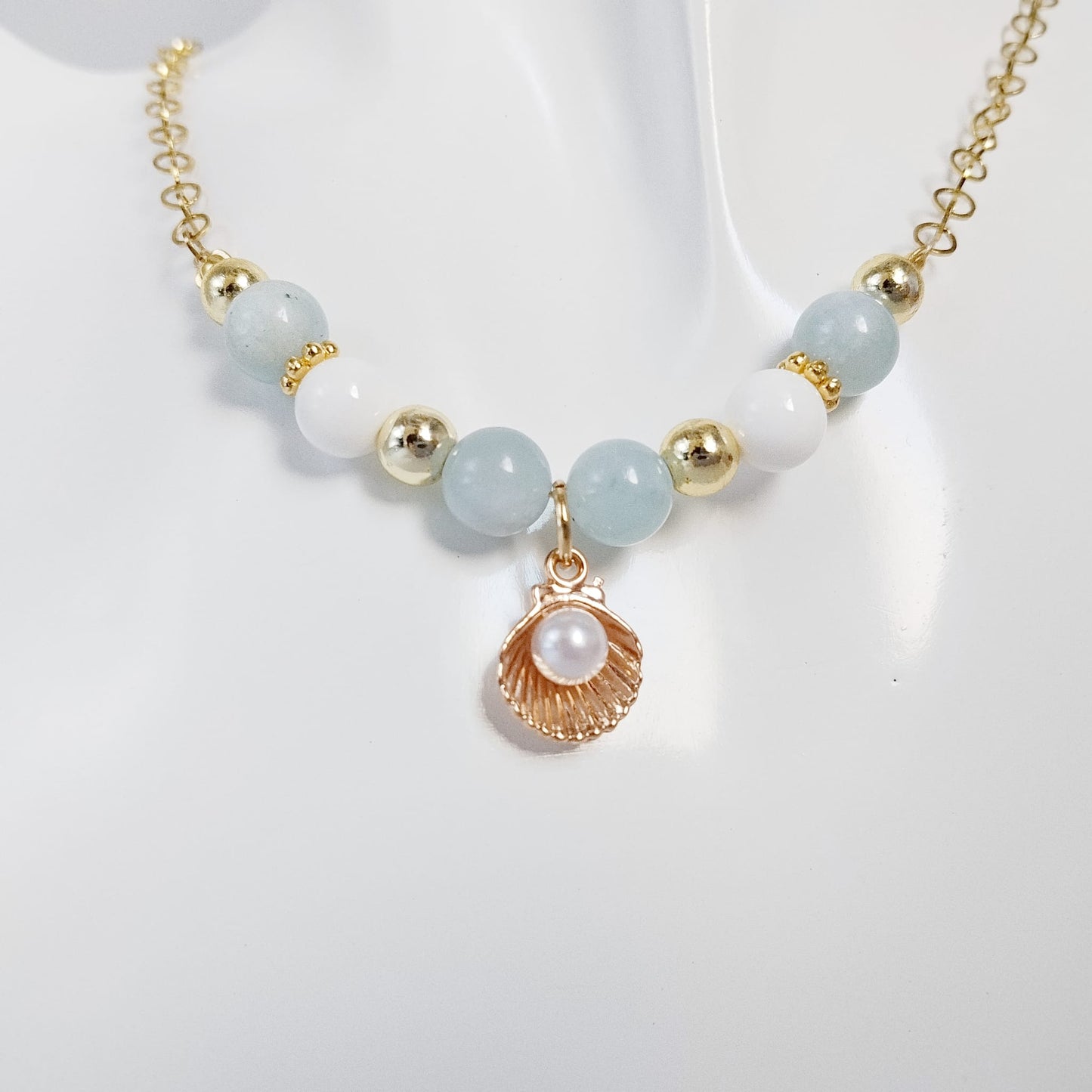 Découvrez le collier en Aigue-Marine, Nacre et son pendentif Saint-Jacques. Un bijou sacré alliant sérénité marine, communication fluide et haute protection vibratoire.