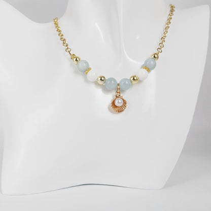 Découvrez le collier en Aigue-Marine, Nacre et son pendentif Saint-Jacques. Un bijou sacré alliant sérénité marine, communication fluide et haute protection vibratoire.