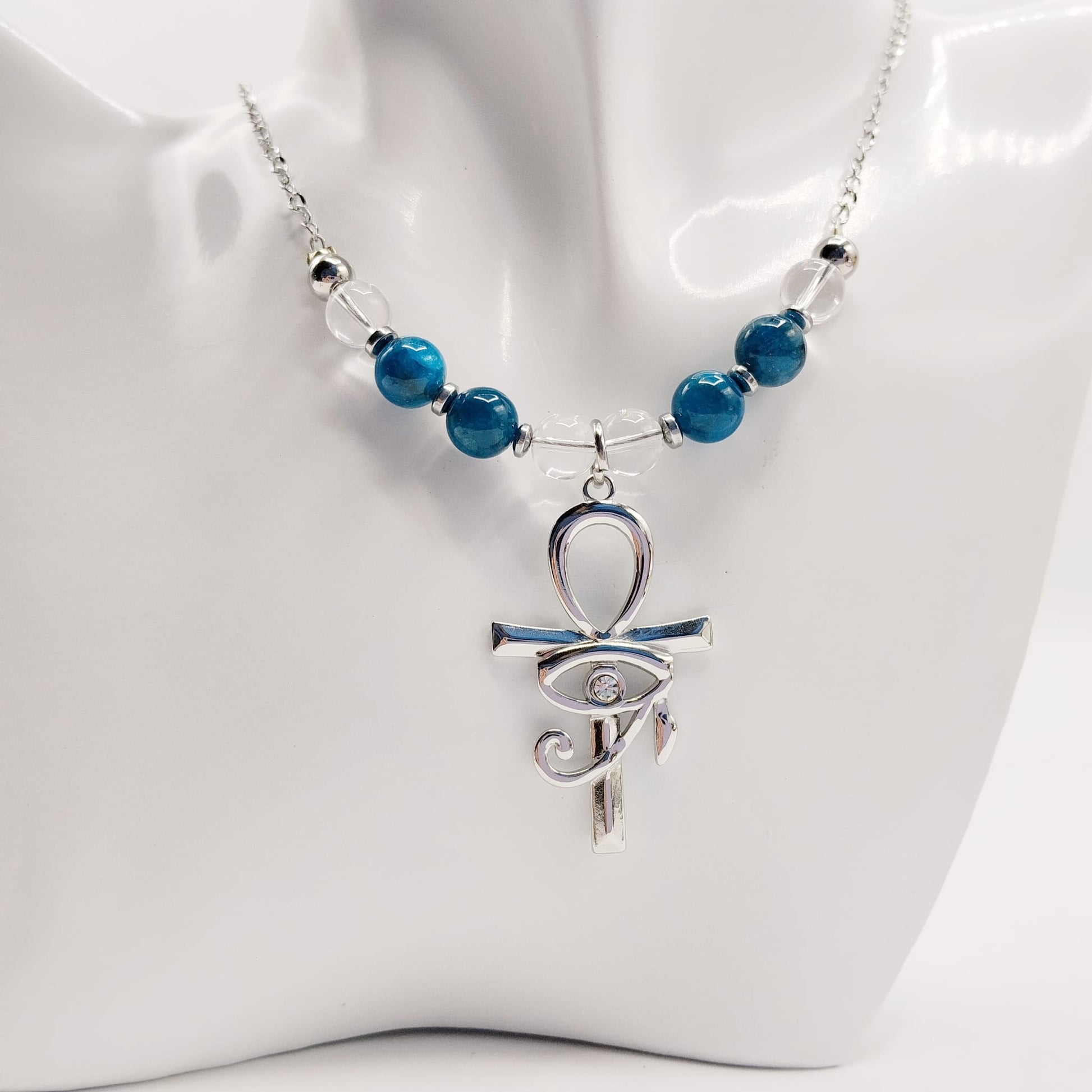 Collier en Apatite et Cristal de Roche avec pendentif Ankh et Œil d’Horus en acier inoxydable. Bijou spirituel favorisant communication, protection et harmonie énergétique.