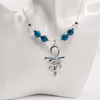 Collier en Apatite et Cristal de Roche avec pendentif Ankh et Œil d’Horus en acier inoxydable. Bijou spirituel favorisant communication, protection et harmonie énergétique.