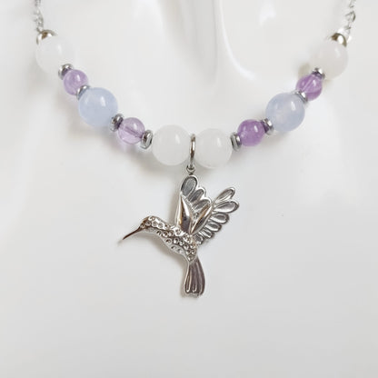 Découvrez notre collier Colibri en Jade blanc, Calcédoine et Améthyste. Un bijou artisanal en pierres naturelles synonyme de sérénité, clarté et douceur.