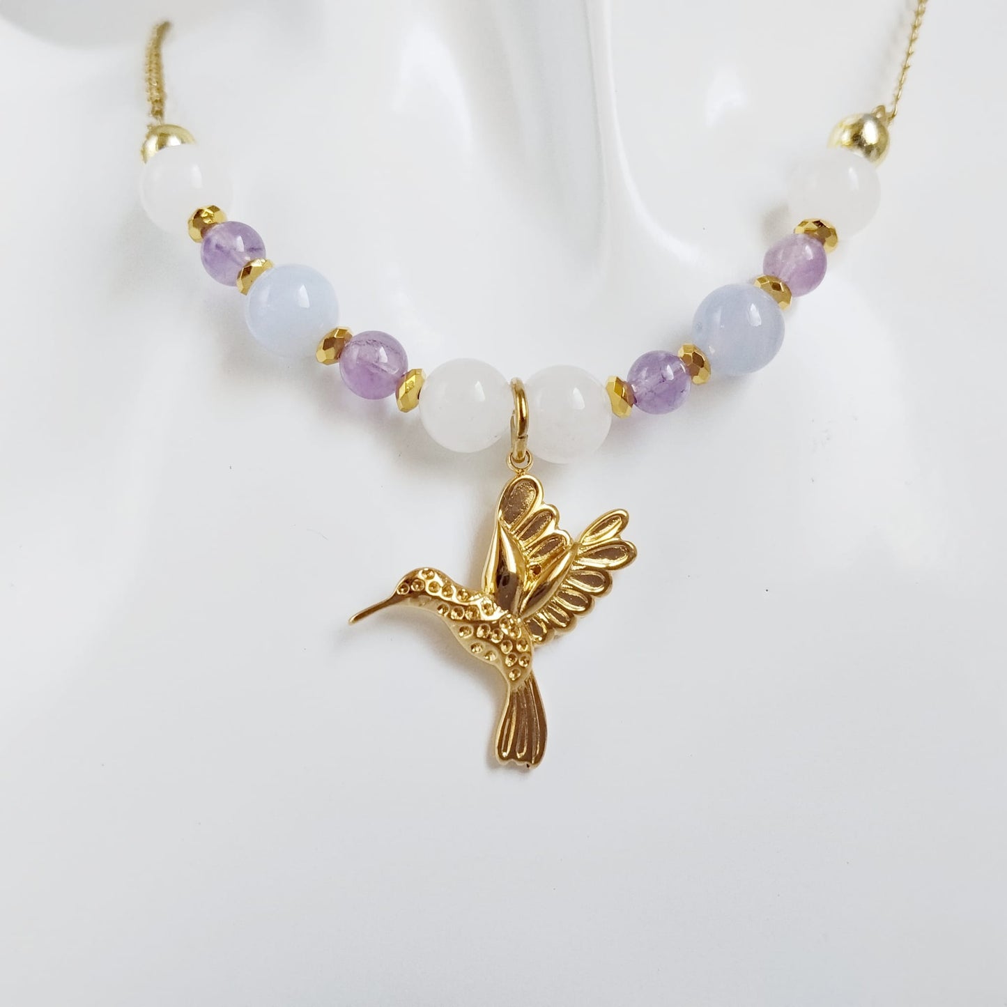 Découvrez notre collier Colibri en Jade blanc, Calcédoine et Améthyste. Un bijou artisanal en pierres naturelles synonyme de sérénité, clarté et douceur.