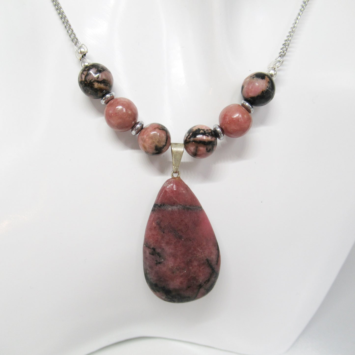 Collier Rhodonite Goutte  https://monjolicaillou.fr/products/collier-rhodonite-goutte  Portez ce bijou avec assurance au quotidien ou lors d'occasions spéciales, et laissez-vous transporter par l'éclat subtil et la sérénité que seule la Rhodonite peut offrir. Avec son mariage parfait entre qualité, style et bien-être, ce collier est bien plus qu'un simple accessoire : c'est une invitation à rayonner 