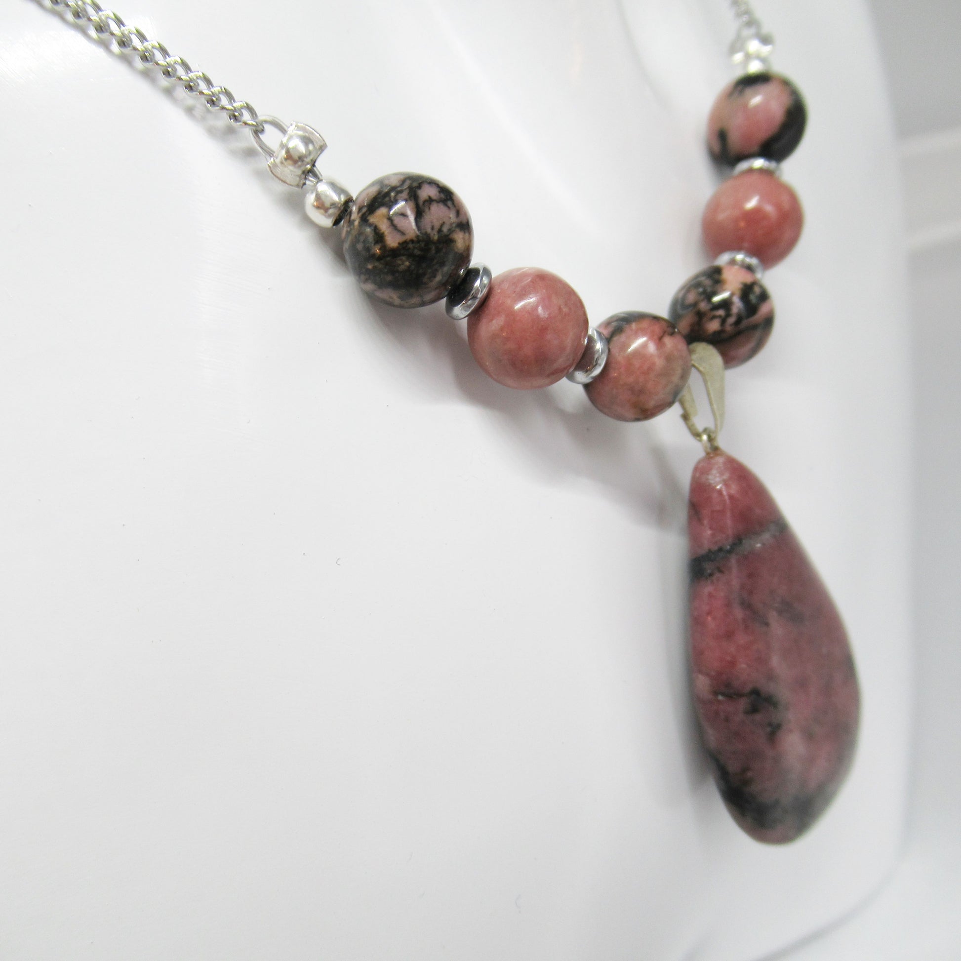 Collier Rhodonite Goutte  https://monjolicaillou.fr/products/collier-rhodonite-goutte  Portez ce bijou avec assurance au quotidien ou lors d'occasions spéciales, et laissez-vous transporter par l'éclat subtil et la sérénité que seule la Rhodonite peut offrir. Avec son mariage parfait entre qualité, style et bien-être, ce collier est bien plus qu'un simple accessoire : c'est une invitation à rayonner 