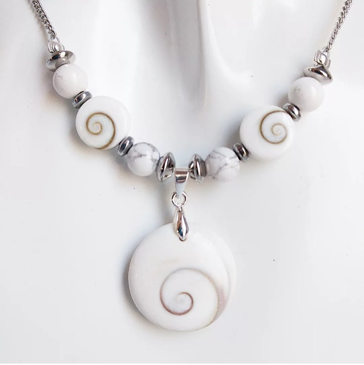 Collier argenté fait main avec Howlite et Œil de Sainte Lucie. Apaisement, protection et élégance réunis dans un bijou porte-bonheur au design raffiné.

