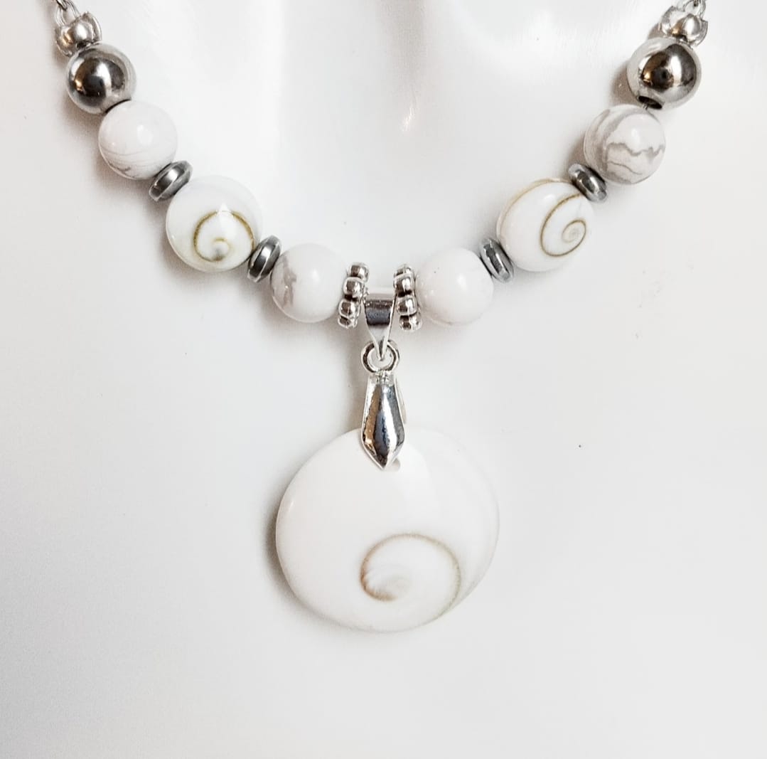 Collier argenté fait main avec Howlite et Œil de Sainte Lucie. Apaisement, protection et élégance réunis dans un bijou porte-bonheur au design raffiné.

