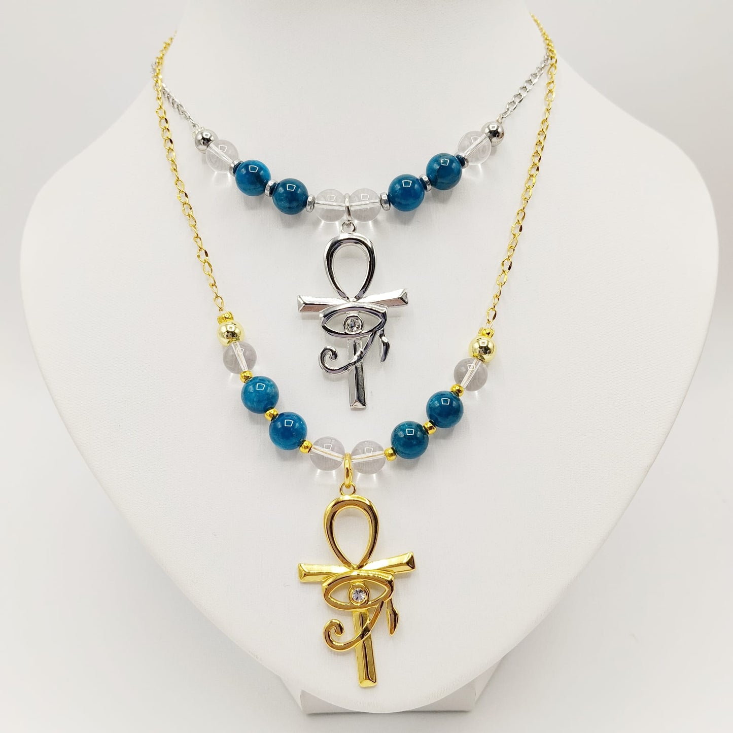Collier en Apatite et Cristal de Roche avec pendentif Ankh et Œil d’Horus en acier inoxydable. Bijou spirituel favorisant communication, protection et harmonie énergétique.