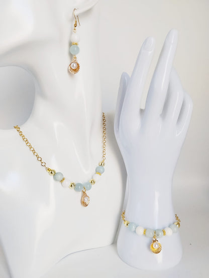 Découvrez le collier en Aigue-Marine, Nacre et son pendentif Saint-Jacques. Un bijou sacré alliant sérénité marine, communication fluide et haute protection vibratoire.